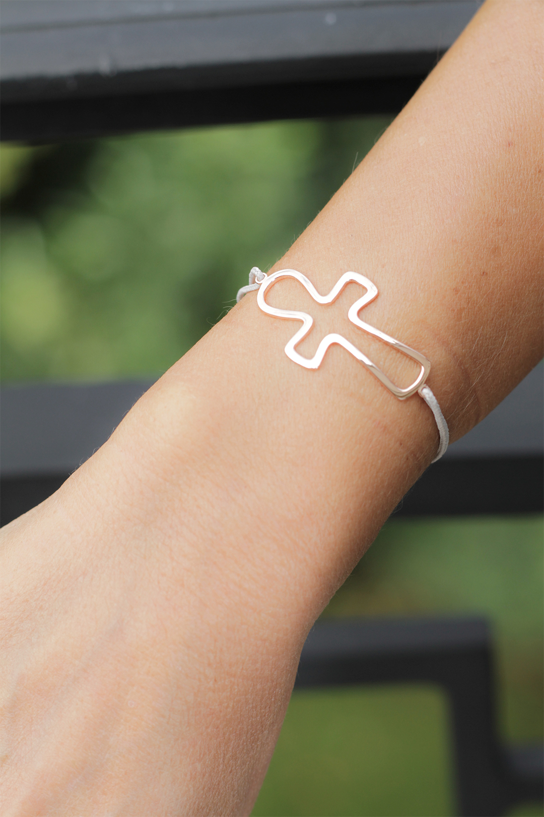 Photographie du bracelet Key of Life en or rose, plan serré sur le poignet d'un modèle féminin. Le bracelet représente une croix égyptienne montée sur un cordon en coton ciré blanc.