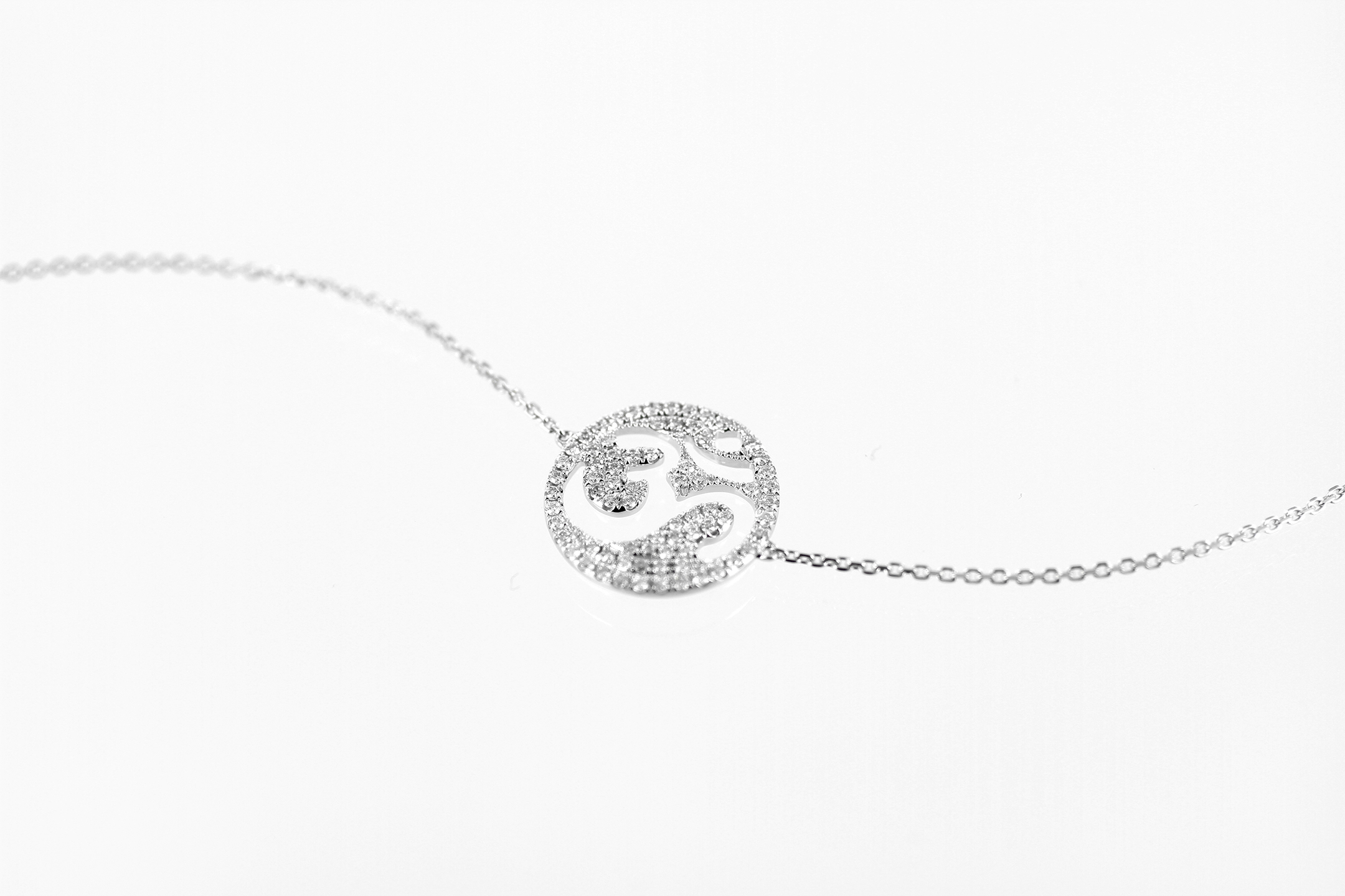 Photographie packshot sur fond blanc du collier OM en or blanc et diamants : il est composé du symbole OM incrusté de diamants, monté sur une chaîne en or blanc très fine.
