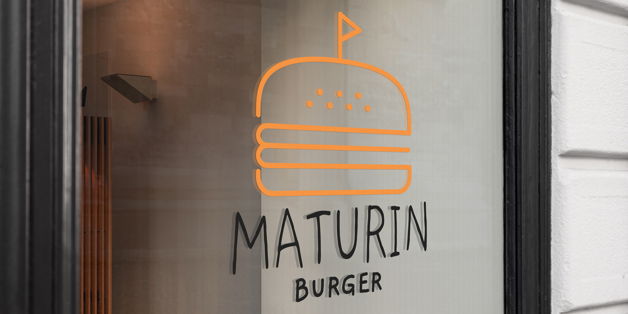 Photographie du logo de Maturin Burger sur une vitrine de restaurant, burger jaune et écriture noire.