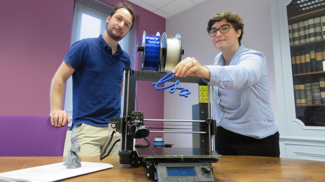 Renaud BERTHIER (à gauche) et Margot MARC (à droite) devant une imprimante 3d, tenant le logo de ls-a